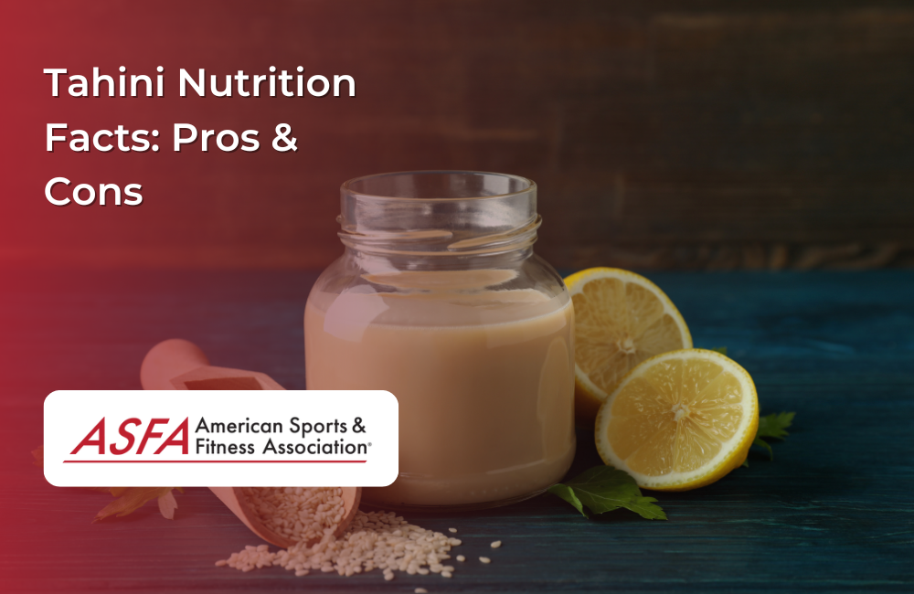 A jar of tahini with a wooden scoop of sesame seeds and sliced lemons on a dark wooden background.