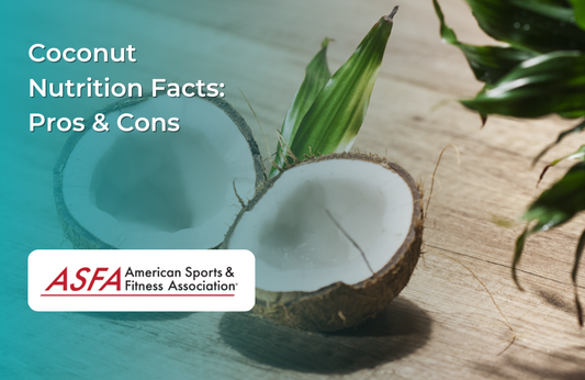 A freshly cut coconut on a wooden surface with green leaves in the background.