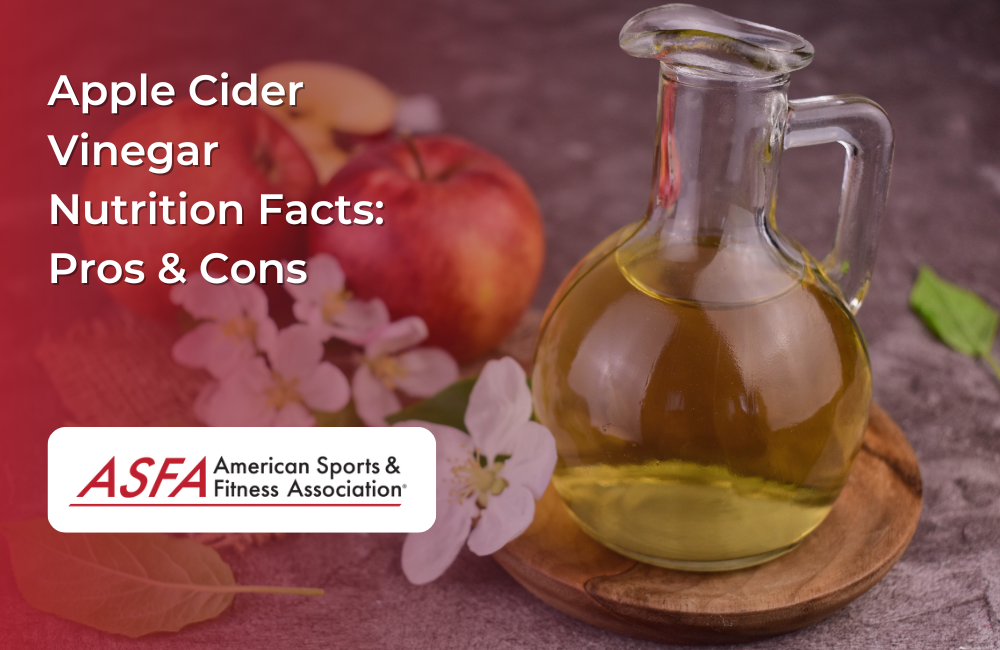 A glass bottle filled with apple cider vinegar surrounded by apples and apple blossoms.