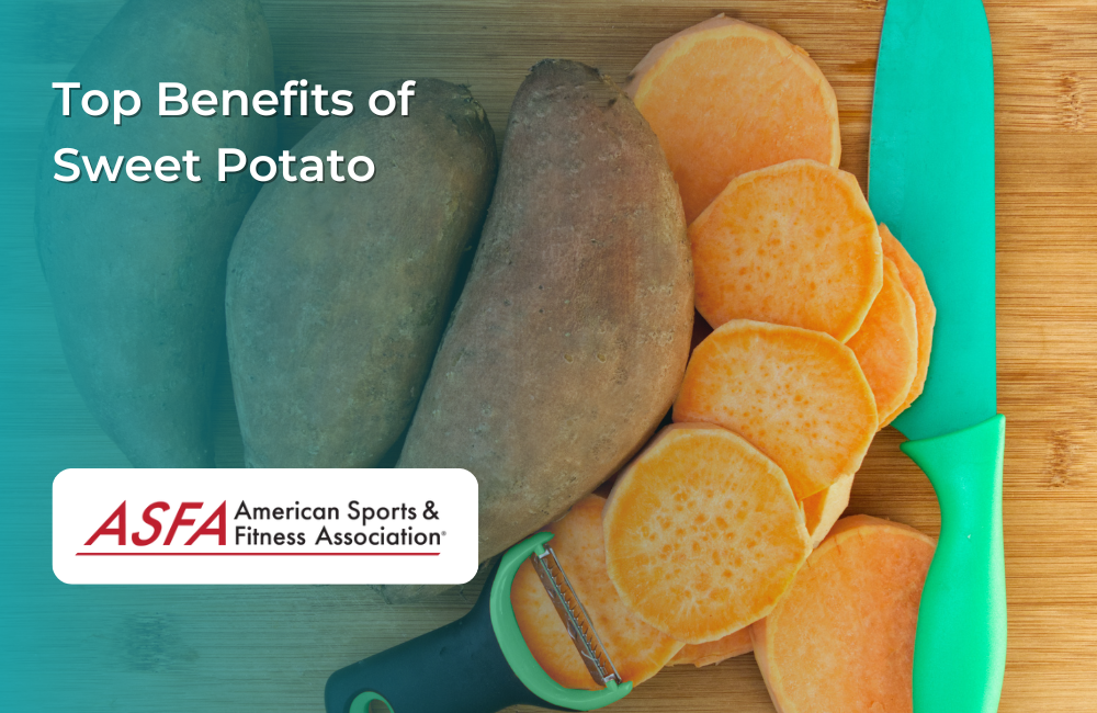 Whole and sliced sweet potatoes on a wooden surface with a green knife and peeler.