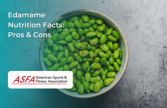 A bowl filled with bright green edamame beans, lightly seasoned with red pepper flakes, on a gray surface.