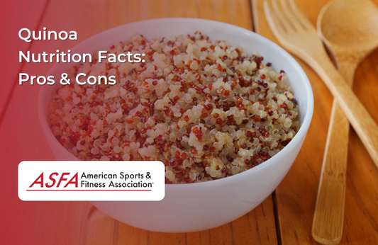 A white bowl filled with cooked quinoa, set on a wooden table with wooden utensils.