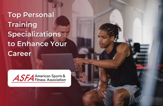 Two men in a gym discussing something on a laptop with fitness equipment in the background.