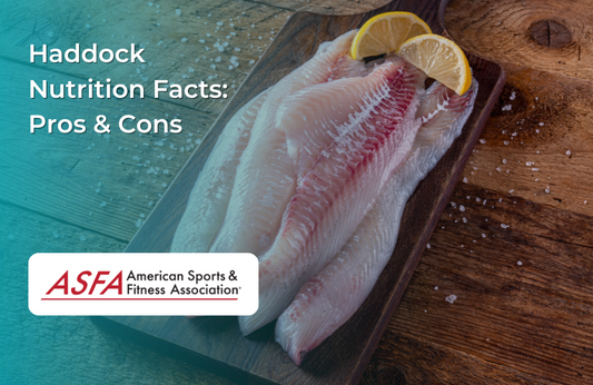 Fresh haddock fillets on a wooden board, garnished with lemon slices and sea salt.
