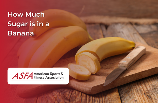 Sliced bananas on a plate with a knife with a bunch of bananas behind it, all on a wood plank surface. .