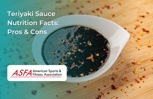 A small white bowl filled with dark teriyaki sauce, garnished with red pepper flakes, placed on a wooden surface.