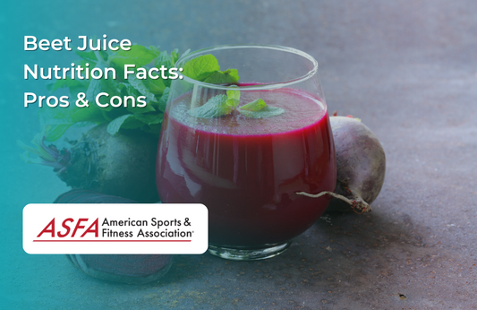 A glass of deep red beet juice garnished with fresh mint leaves, with whole beets in the background.
