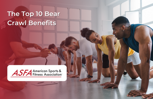 A group of people in athletic wear in bear crawl position on a gym floor with a coach guiding them.