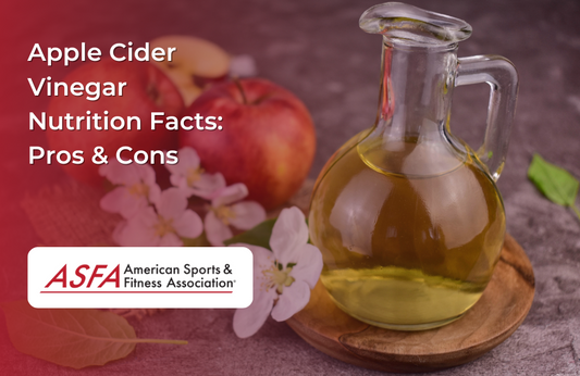 A glass bottle filled with apple cider vinegar surrounded by apples and apple blossoms.
