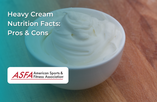 A white bowl filled with thick, whipped heavy cream, placed on a wooden surface.