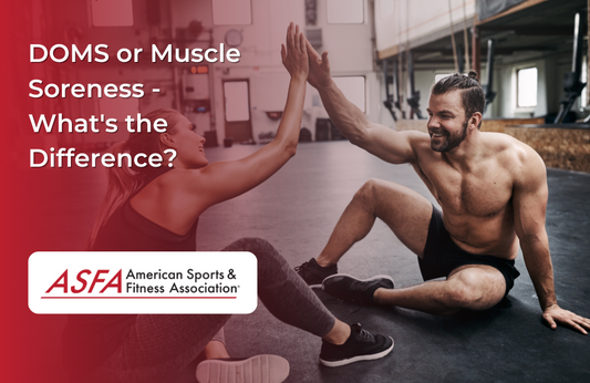 A man and a woman in gym wear sitting on the floor, smiling and giving each other a high five.