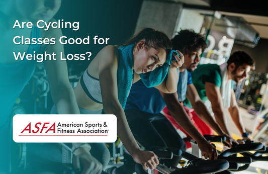 A group of people engaged in an indoor cycling class at a gym.