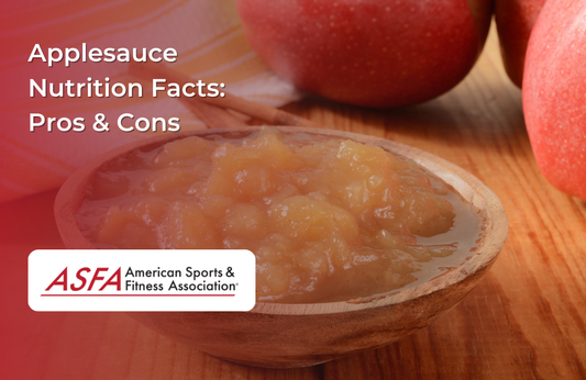 A bowl of fresh applesauce with whole apples in the background.
