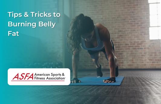 A woman in a gym doing a plank on a blue yoga mat, focused.