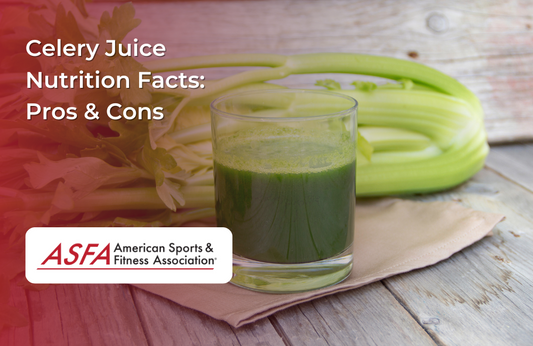 A glass of green celery juice placed on a wooden surface with fresh celery stalks in the background.