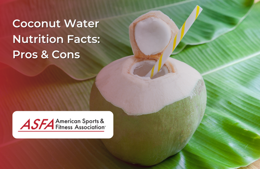A fresh coconut with a straw inserted, sitting on a large green leaf.
