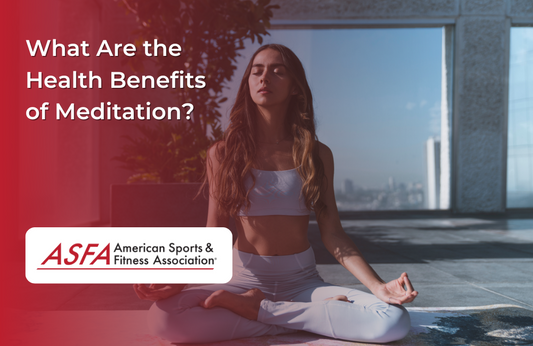 A woman in white athletic wear meditating in a sunlit room.