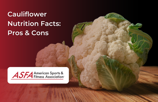 A head of cauliflower with green leaves still attached, placed on a wooden surface.