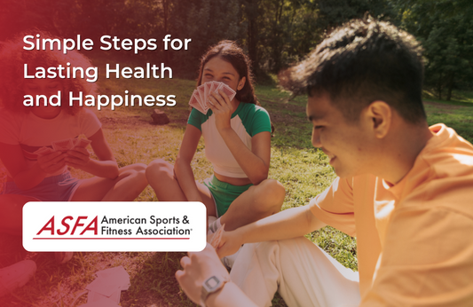 Three people sit on the grass in a sunny park laughing and playing cards together.