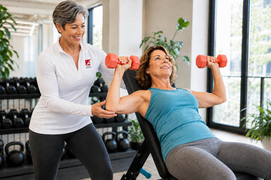 ASFA menopause fitness instructor in a white shirt coaches a midlife woman through an incline dumbbell press